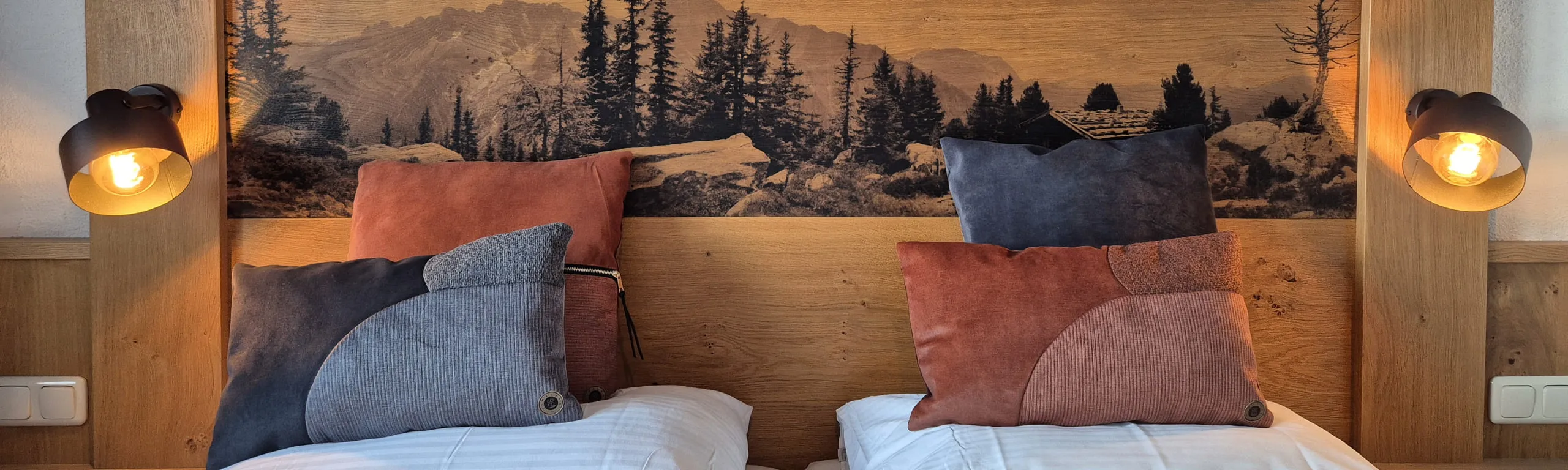 Zwei Betten mit dekorativen Kissen und einer Waldlandschaft im Hintergrund