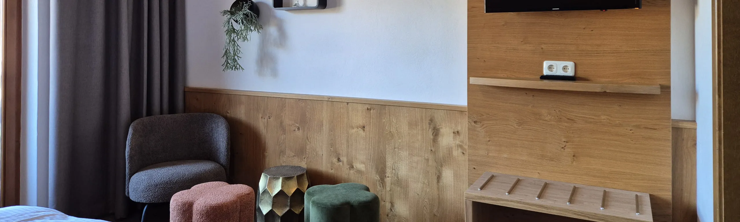 Moderne Zimmeransicht mit Stuhl, Hocker und Fernseher an der Wand