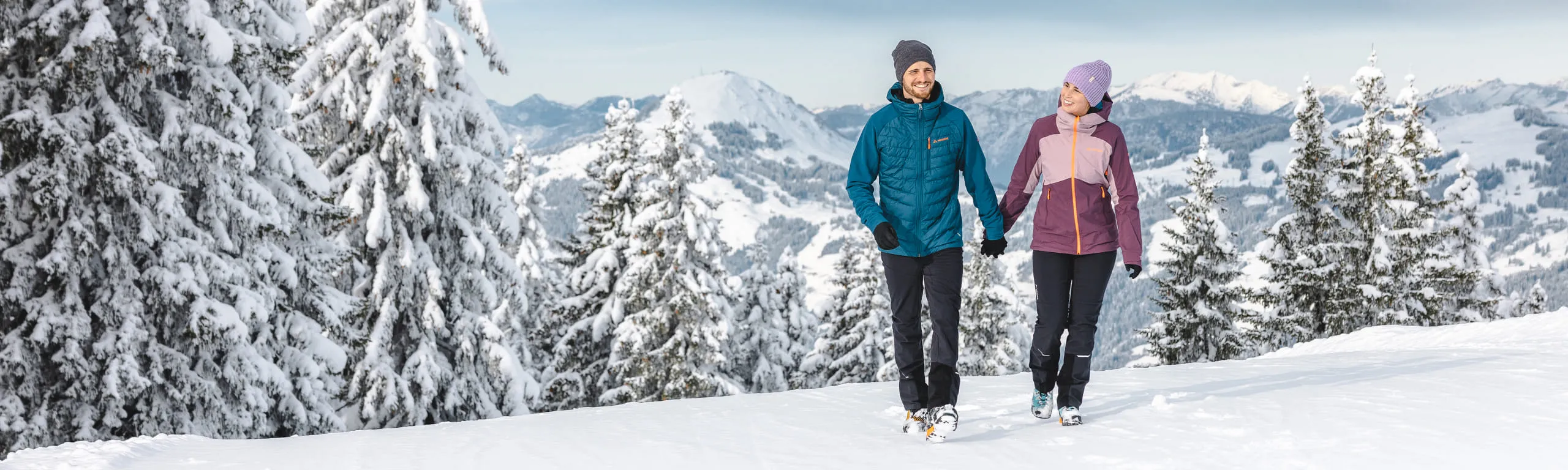 Zwei Personen wandern in einer verschneiten Winterlandschaft.