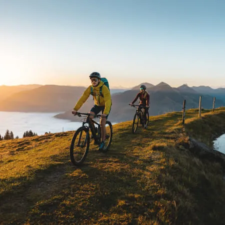 Zwei Radfahrer im Brixental bei Sonnenuntergang auf einem Wanderweg