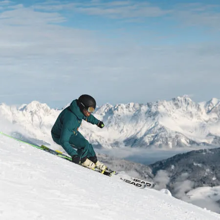 Skifahrer auf einer Piste mit verschneiten Bergen im Hintergrund