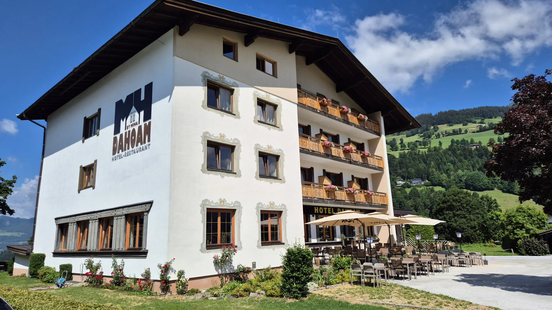 Hotelansicht im Sommer mit Terrasse und Bergblick