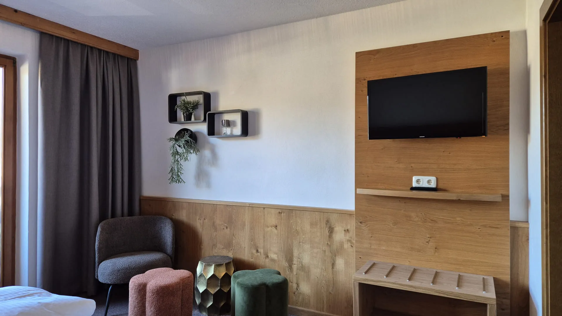 Gemütliches Zimmer mit Fernseher, bequemen Sitzgelegenheiten und Holzdetails