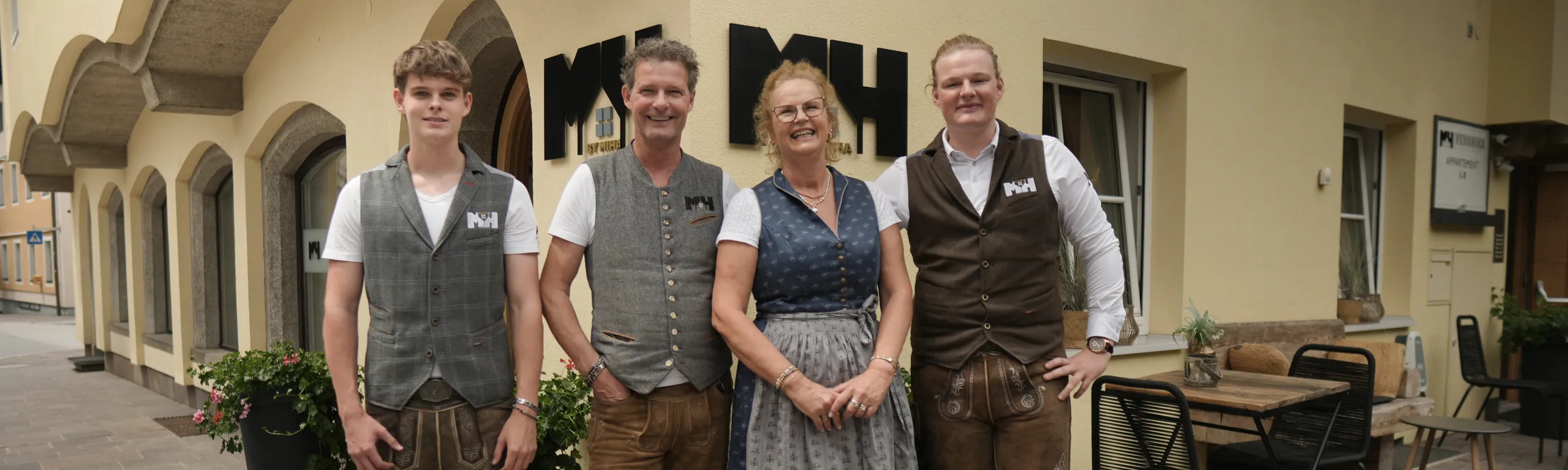 Familie vor einem Restaurant, alle in traditioneller Kleidung.