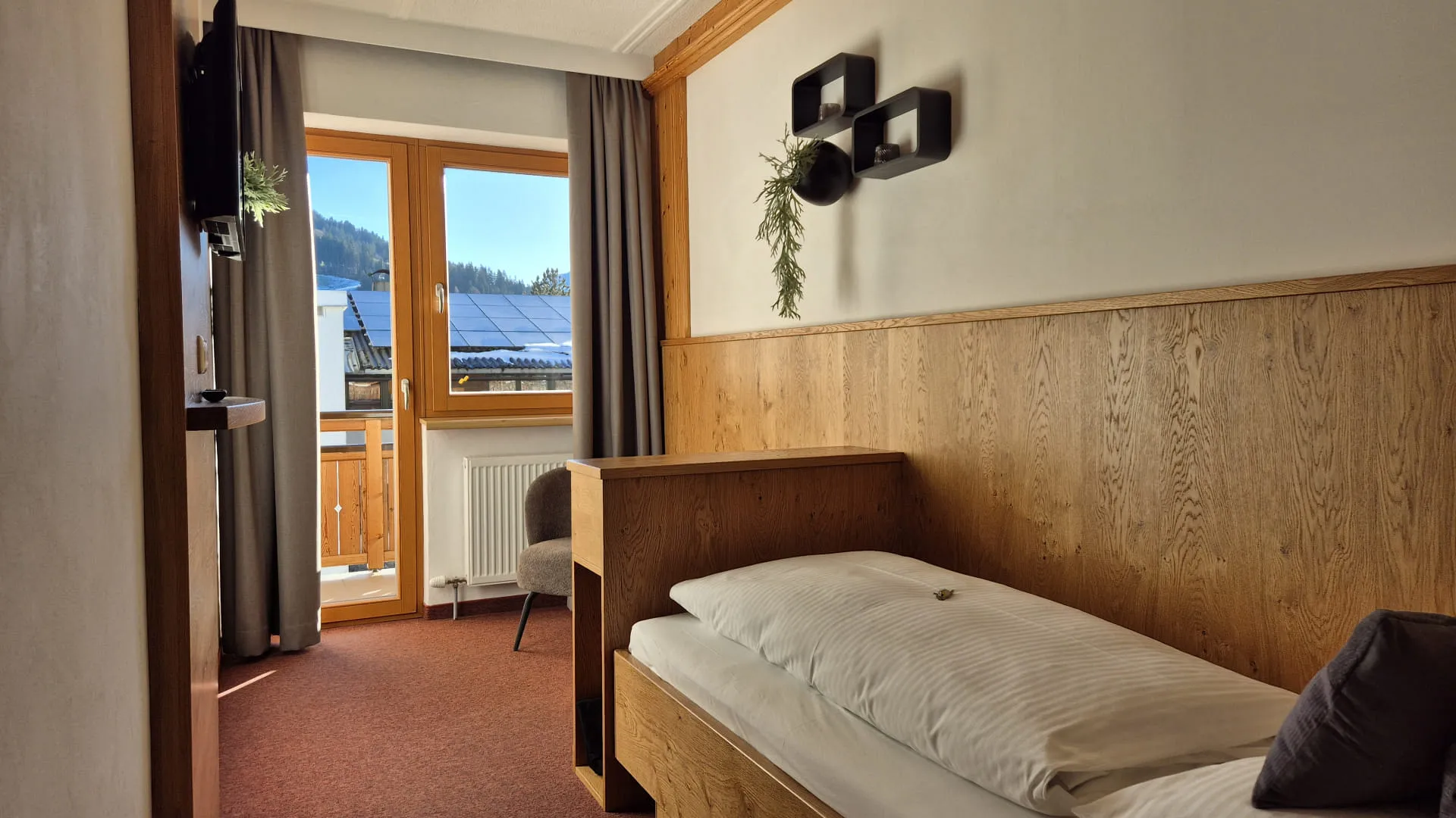 Helles Zimmer mit Holzdekor, Betten und Fenster mit Aussicht.