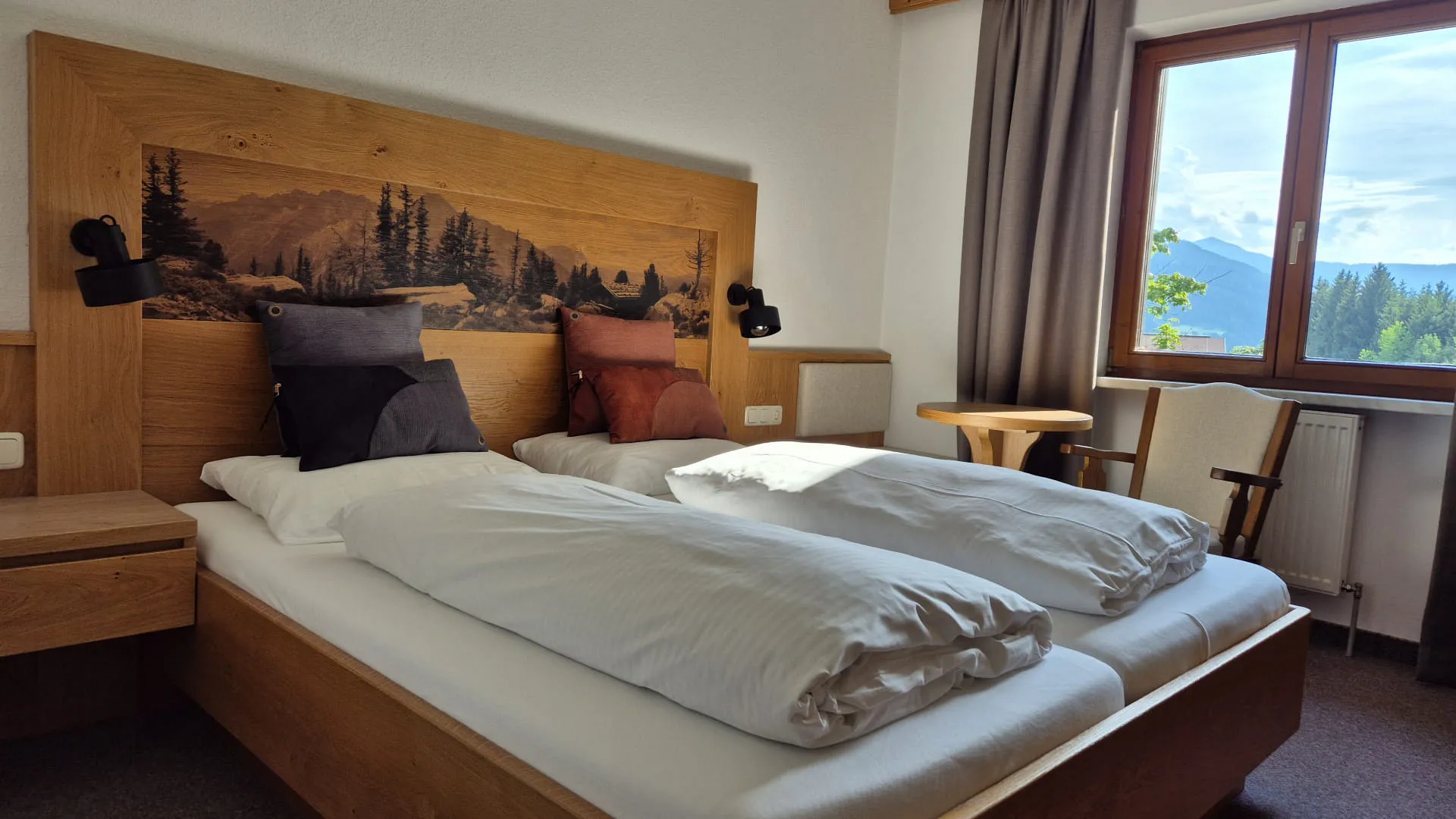 Helles Schlafzimmer mit Holzdeko und Bergblick.