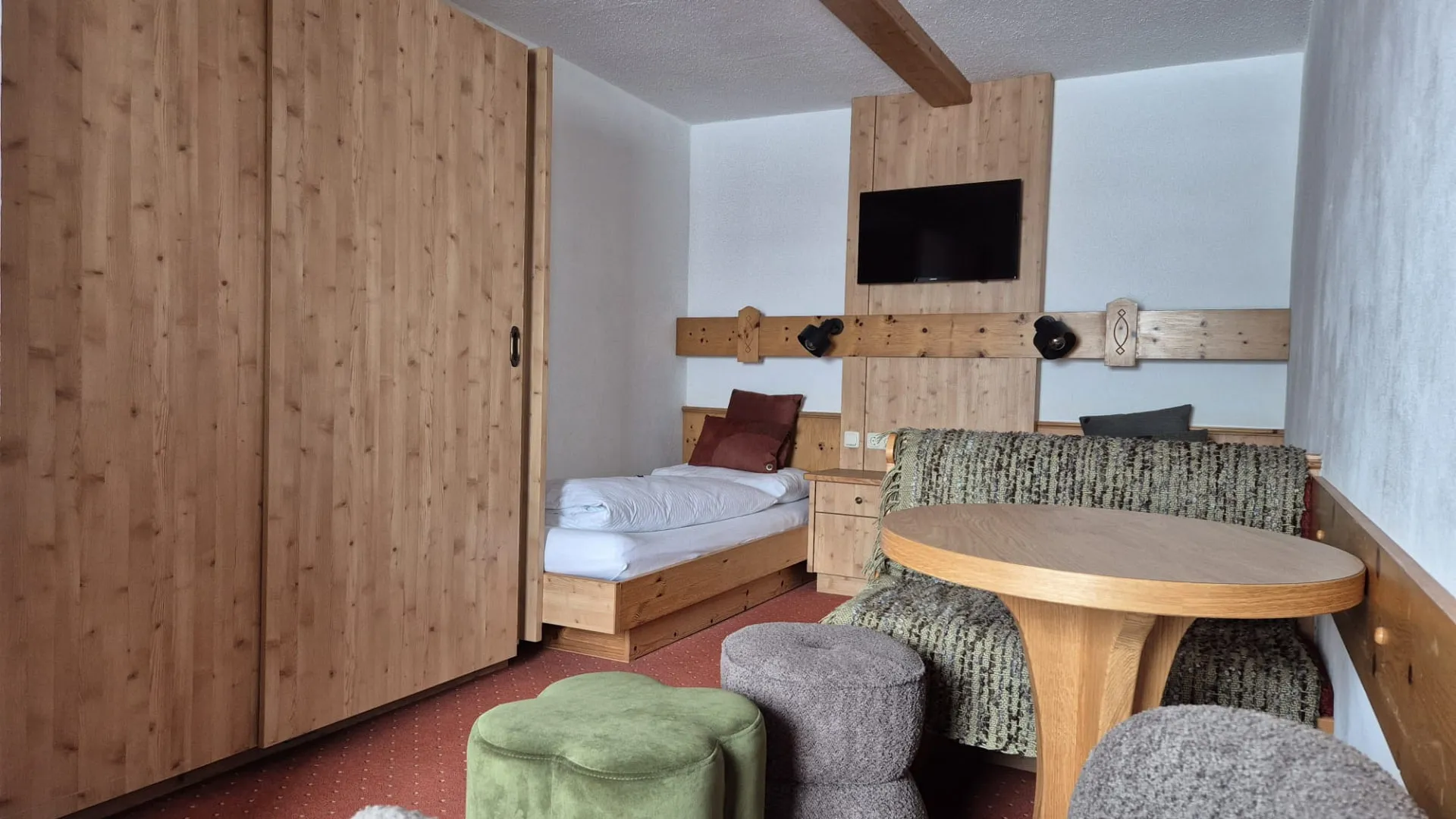 Holzverkleideter Raum mit einem Bett, Tisch und Stühlen