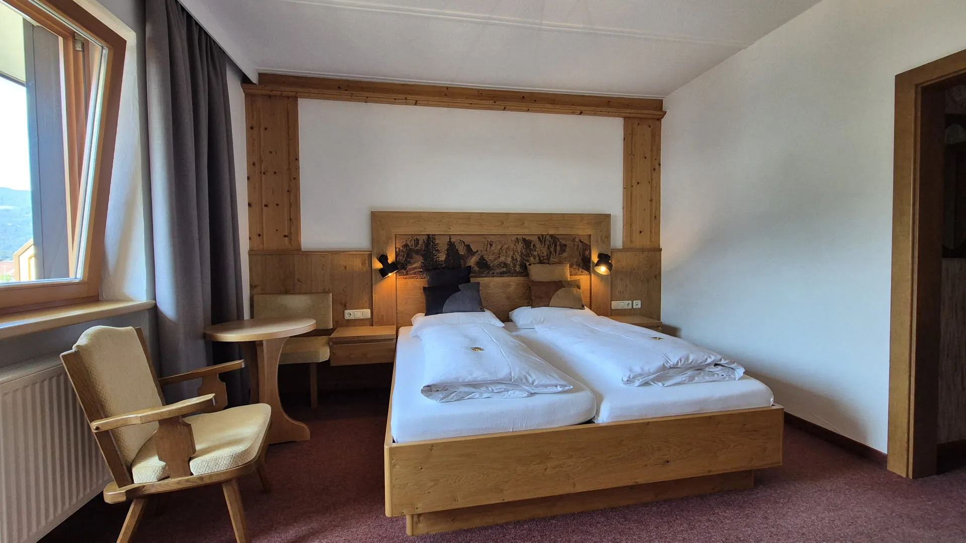 Helles Schlafzimmer mit zwei Betten und Holzregal.