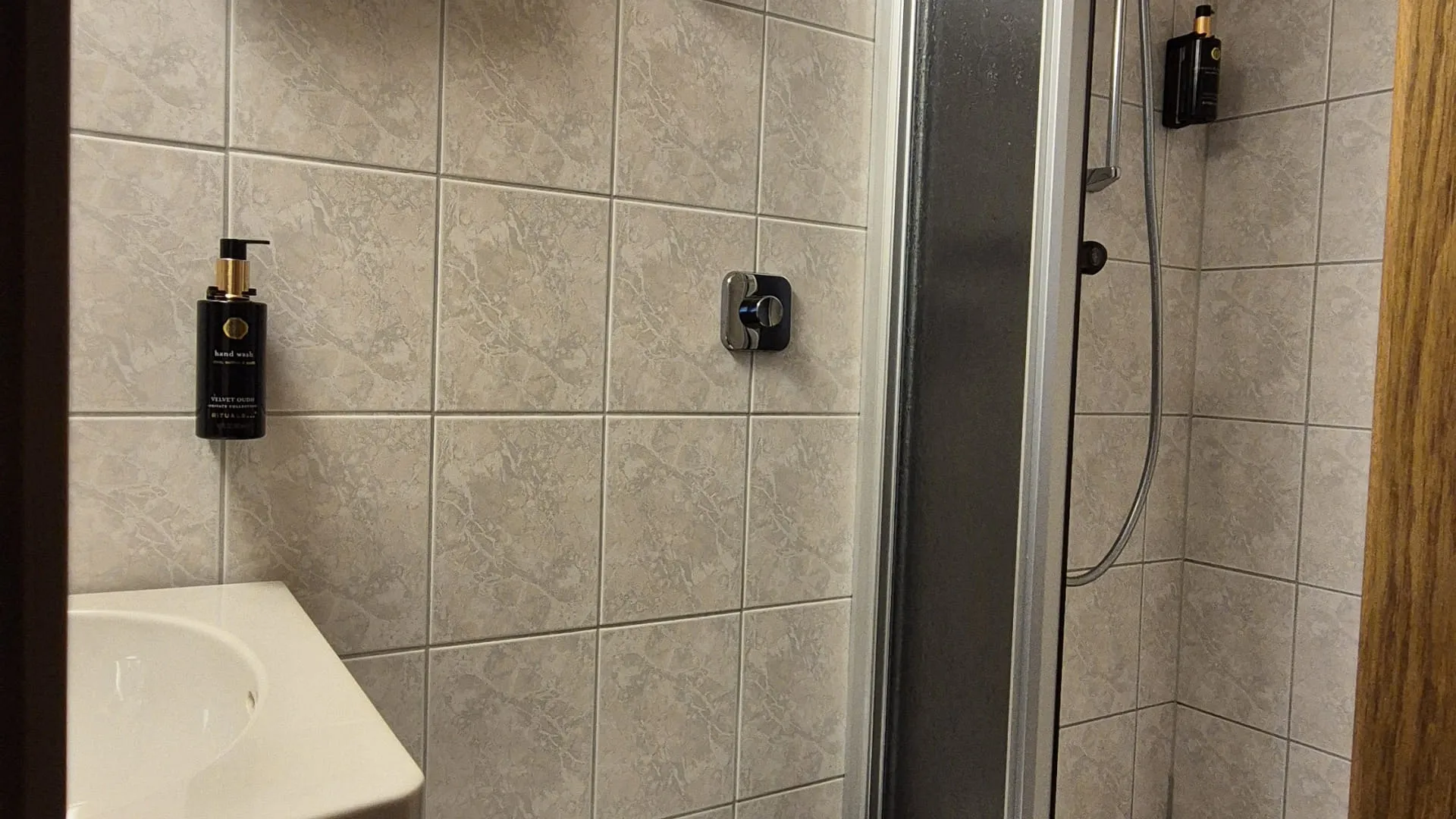 Badezimmer mit Dusche, WC und Handtüchern an der Wand.