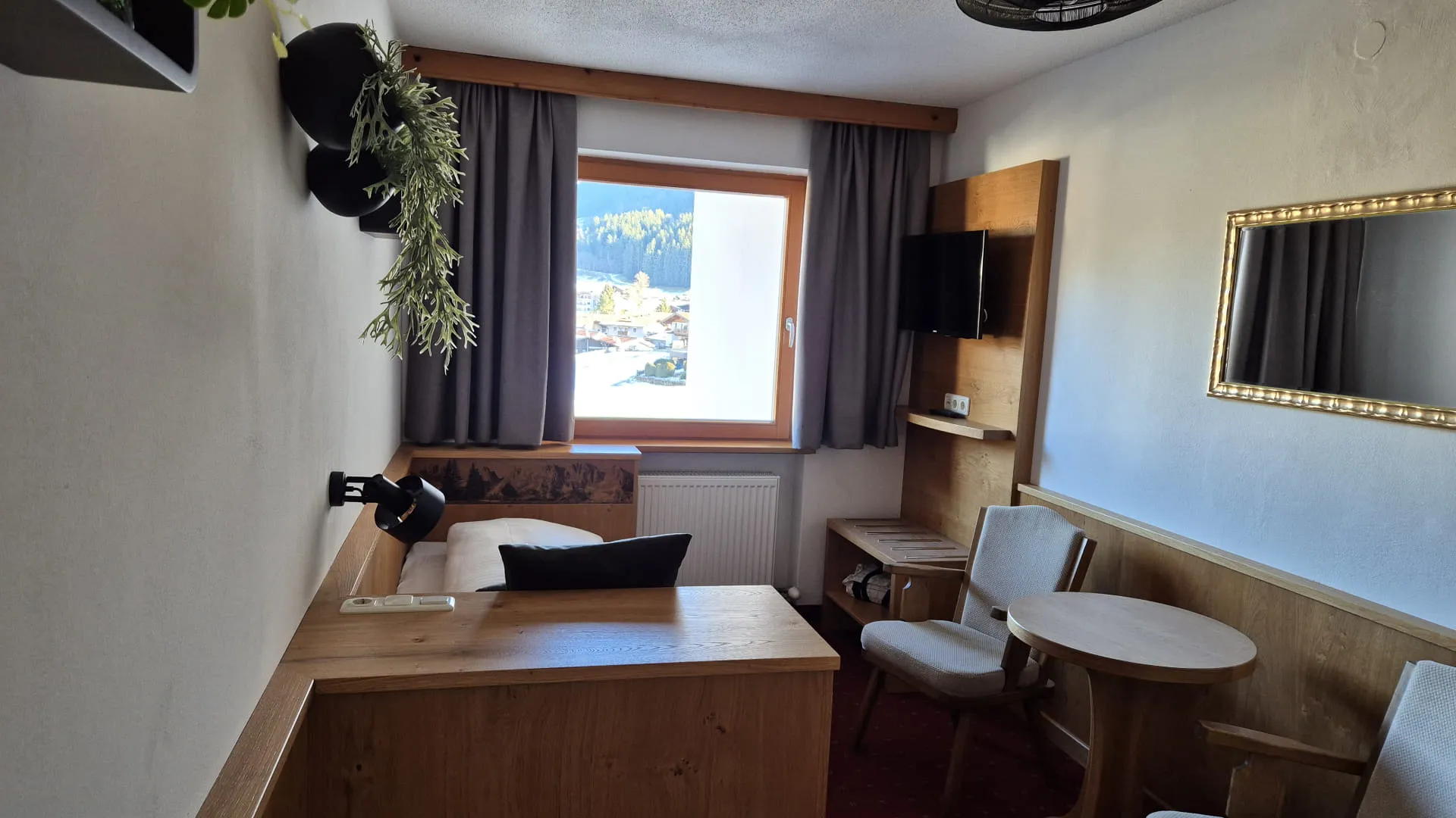 Einblick in ein Hotelzimmer mit Fenster, Bett und Sitzgelegenheiten.